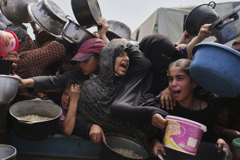 Palestinian children jostle for donated food at a distribution center in Khan Younis in the Gaza Strip on April 21, 2025. (Abdel Kareem Hana / AP)